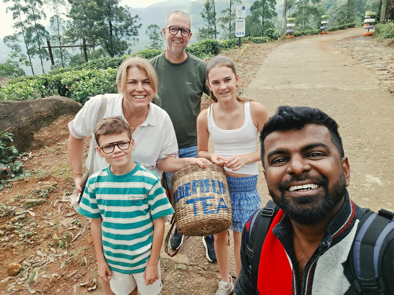 Jorine, Niels and their kids with Dhanuka at a tea plantation, holding a tea-picking basket