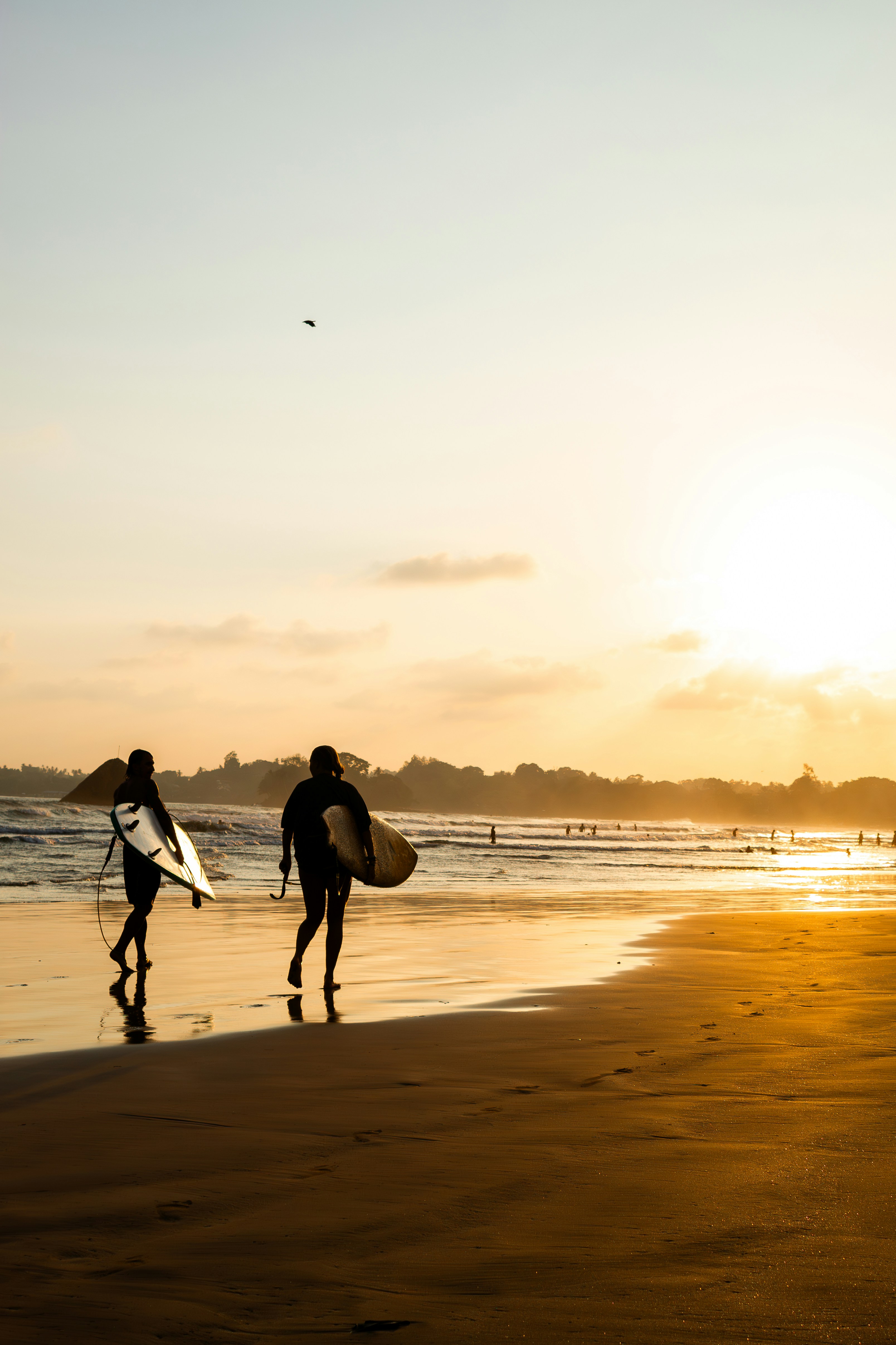 Surfers riding waves at Arugam Bay sunset