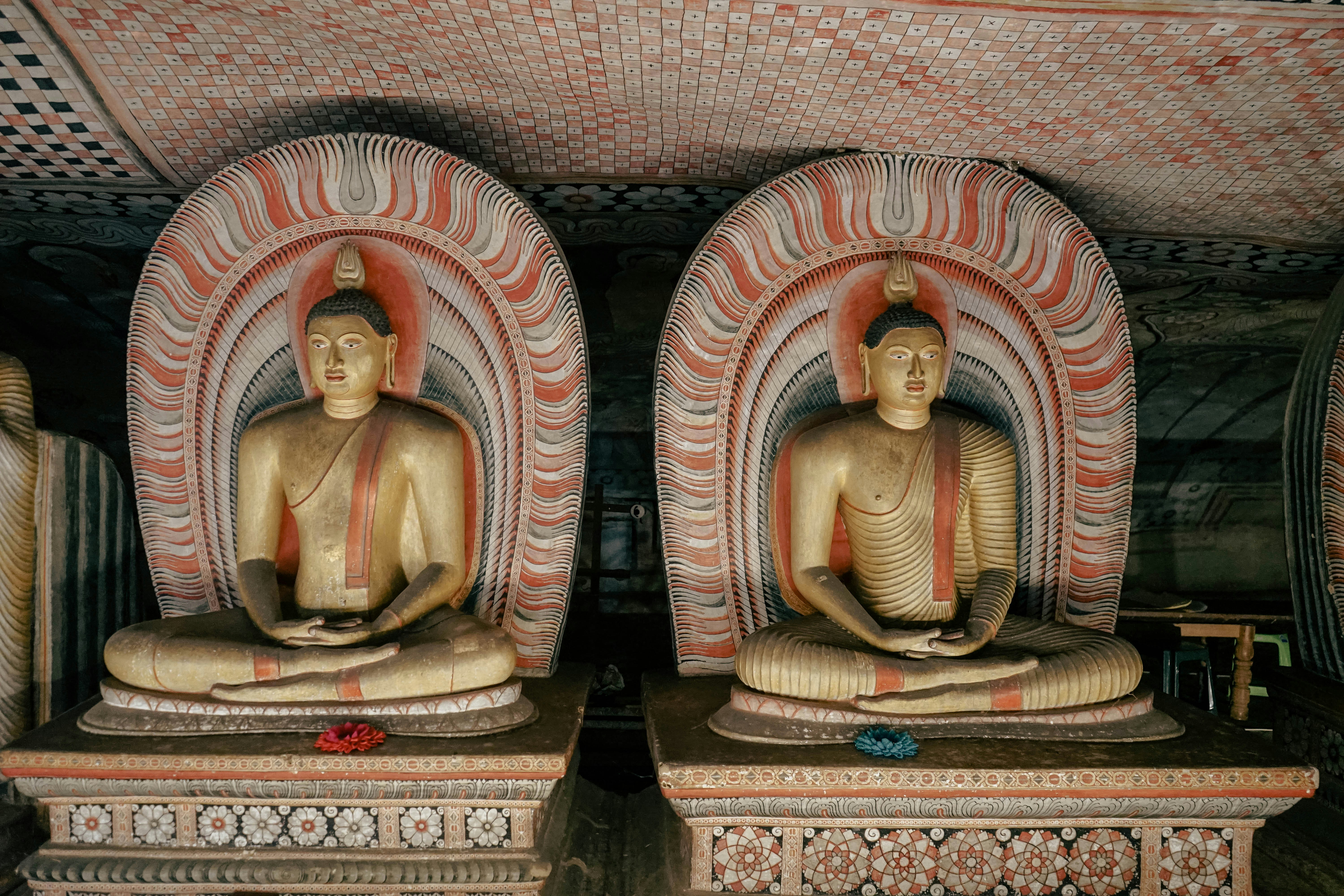 Two seated Buddha statues beneath the painted ceiling of a Dambulla cave temple