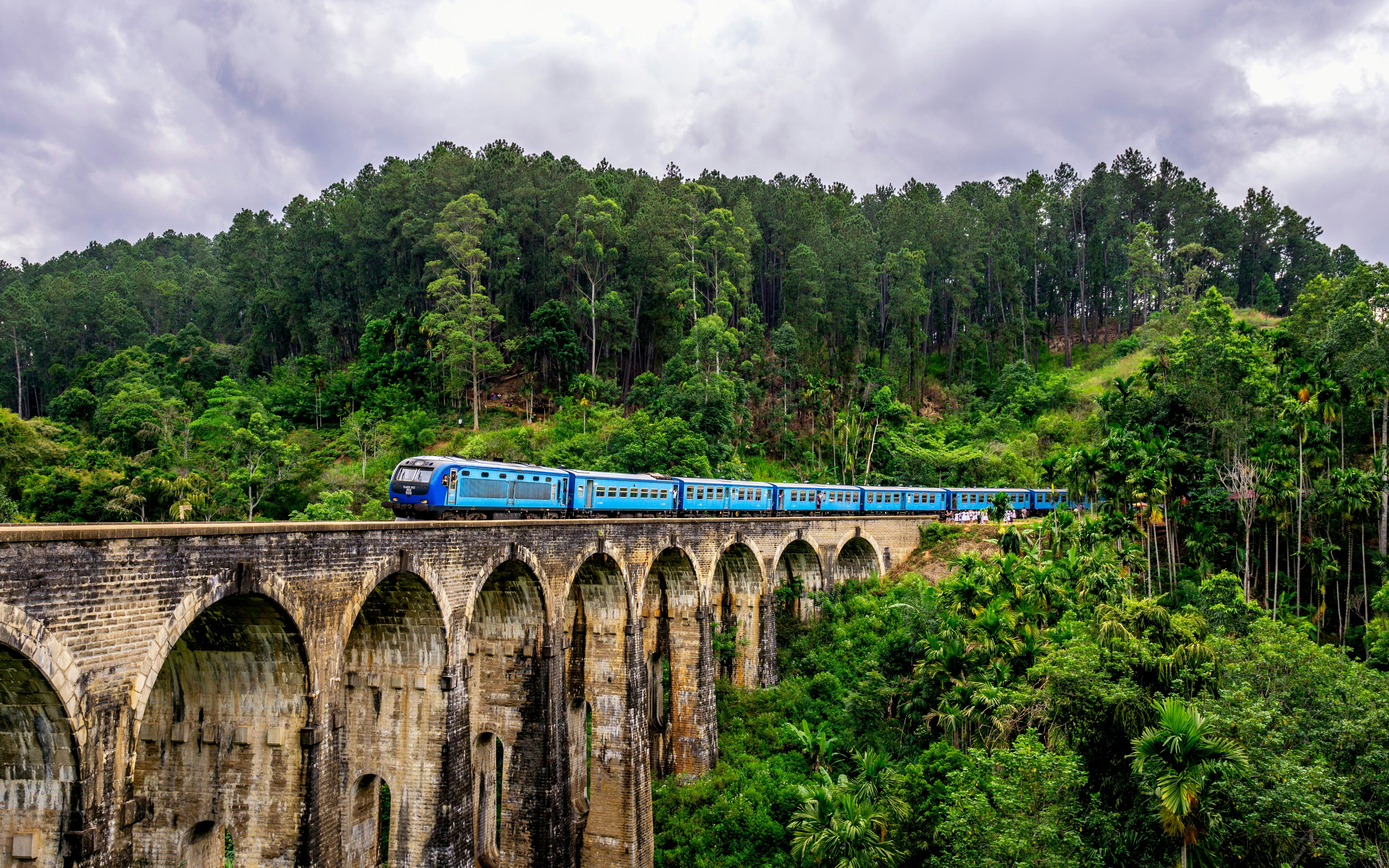 Blue hill-country train crossing the Nine Arches Bridge at Ella